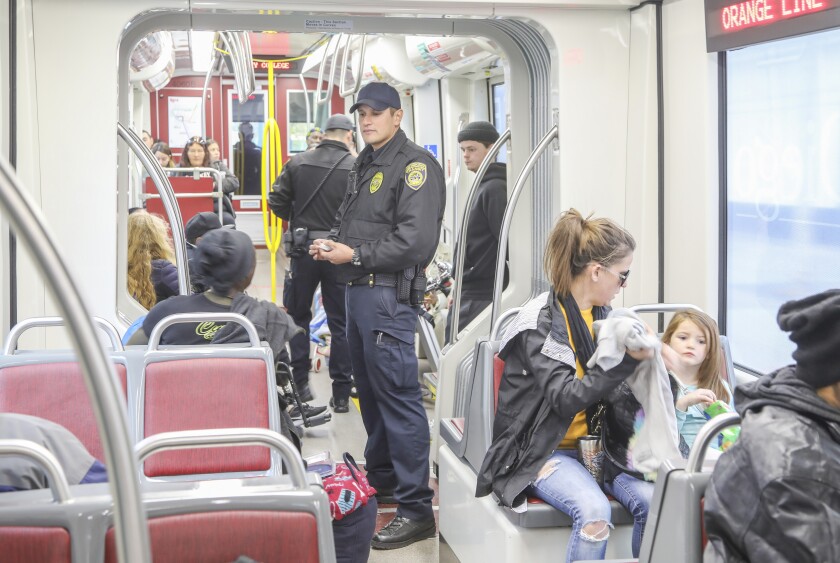MTS transit officer Marc Vargas (middle) asks a woman to display a valid fare on the Orange Line trolley. 