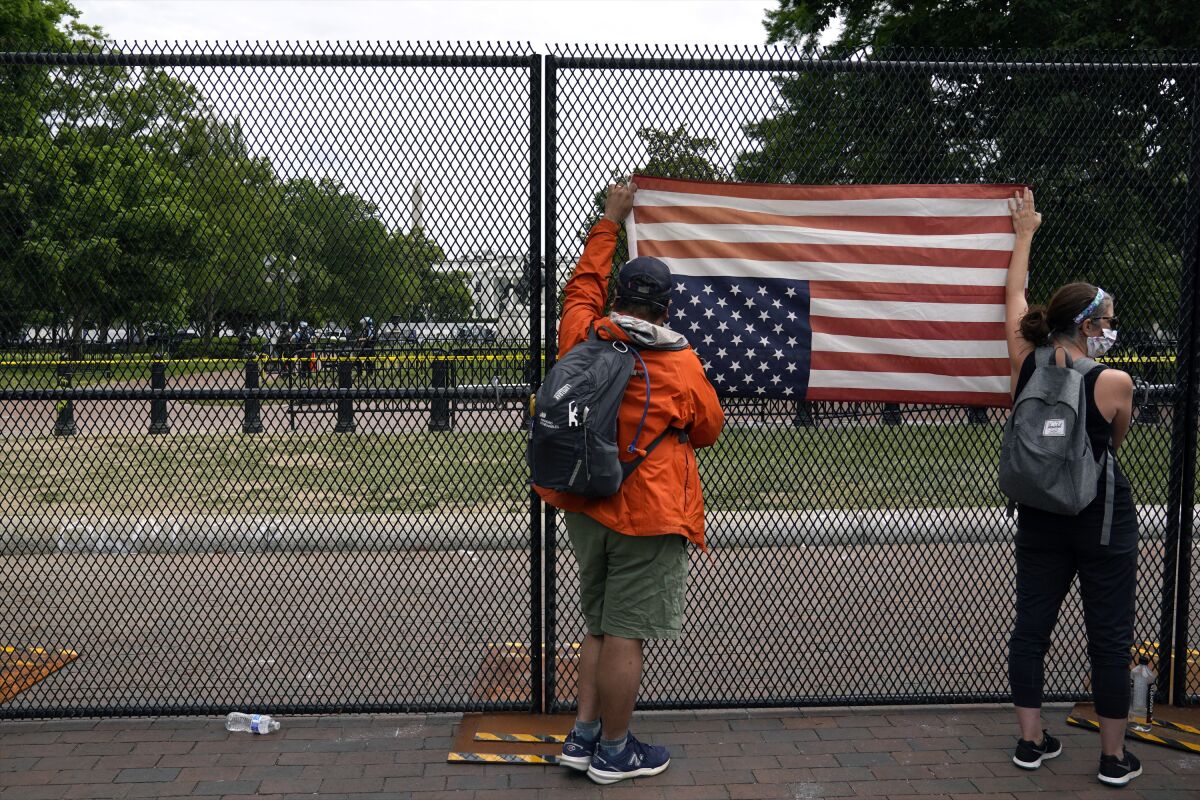 Demonstrators hold a U.S. flag upside down at the fence that now surrounds Lafayette Park, north of the White House.