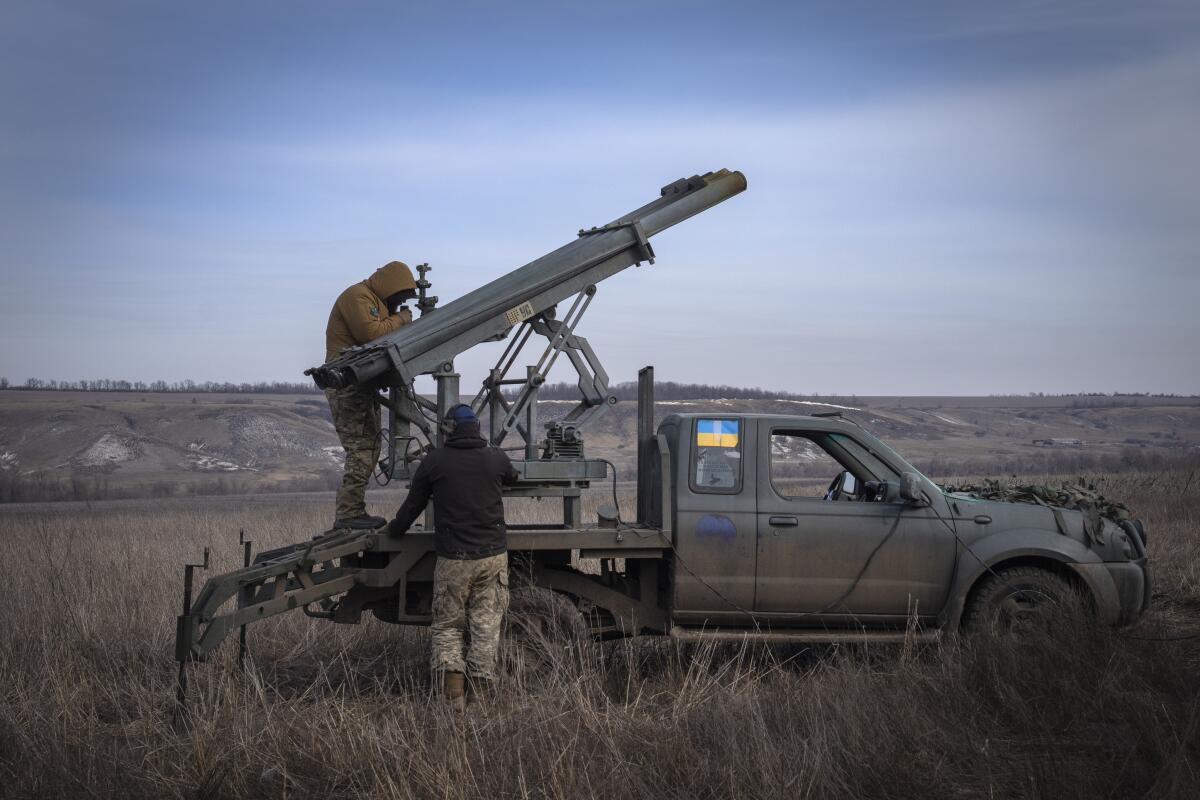 Ukrainian soldiers prepare to fire a rocket system on a pickup truck.