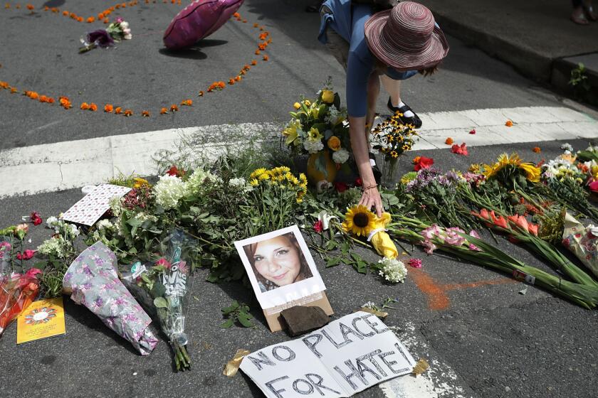 A woman places flowers at a memorial to 32-year-old Heather Heyer, who was killed when a car plowed into a crowd of people protesting the white nationalist Unite the Right rally in Charlottesville, Va.