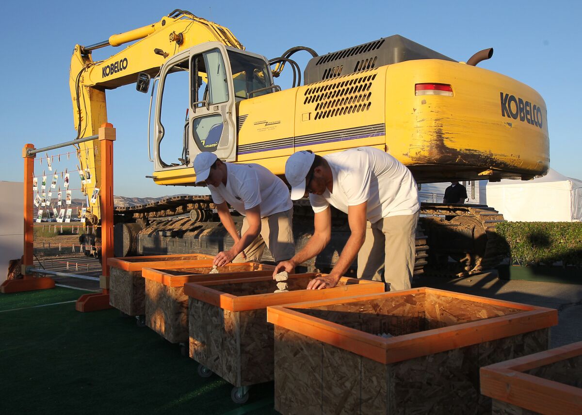 Volunteers organize pieces of the concrete from broken-up runways to be given away as mementos during a recent groundbreaking at the Great Park.
