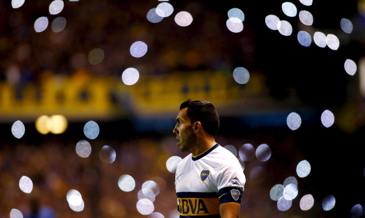 Boca Juniors' striker Carlos Tevez walks on the field as cell phone flash lights light up the background during their Argentine First Division soccer match against Tigre in Buenos Aires, Argentina