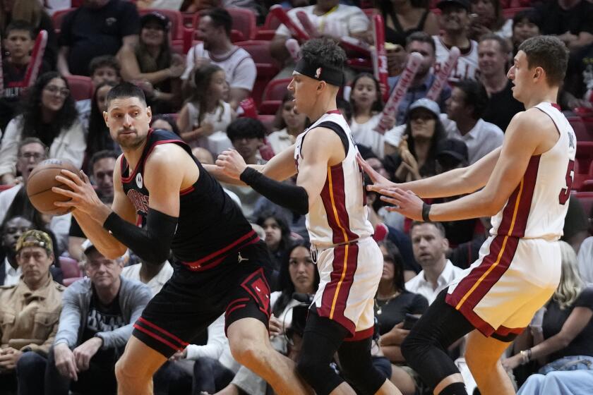 Chicago Bulls center Nikola Vucevic, left, looks for an opening past Miami Heat guard Tyler Herro, center, and forward Nikola Jovic, right, during the first half of an NBA basketball play-in tournament game, Friday, April 19, 2024, in Miami. (AP Photo/Wilfredo Lee)