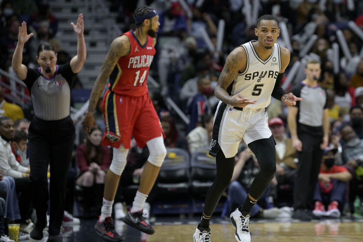 San Antonio Spurs guard Dejounte Murray (5) signals after making a 3-point basket against New Orleans Pelicans forward Brandon Ingram (14) in the second half of an NBA basketball game in New Orleans, Saturday, Feb. 12, 2022. (AP Photo/Matthew Hinton)