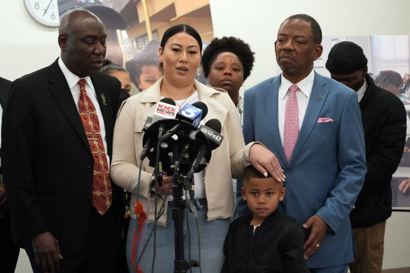 Laywers Benjamin Crump, left, and Carl Douglas, right, hold a news conference with Gabrielle Hansel, guardian of five-year-old Syncere Kai Anderson, to announce filing a $50 million in damages claim against the city of Los Angeles over the death of Keenan Anderson, at a news conference in Los Angeles Friday, Jan. 20, 2023. (AP Photo/Damian Dovarganes)