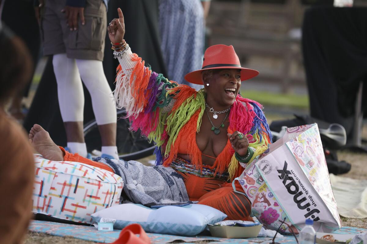 Zhratica Blue sits in a picnic blanket, arm raised