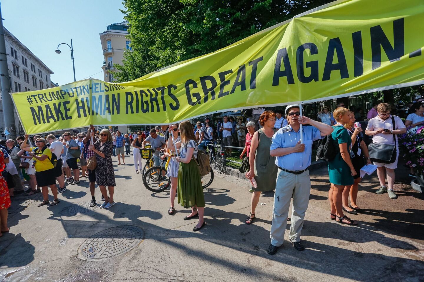 Demonstrators hold a banner calling for human rights and democracy during protests in Helsinki, Finland, during President Trump's visit to the nation.
