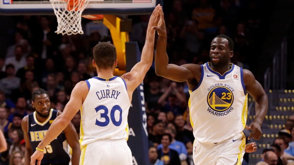 Forward Draymond Green high fives Stephen Curry after Curry hit a three pointer against the Denver Nuggets during the third quarter.