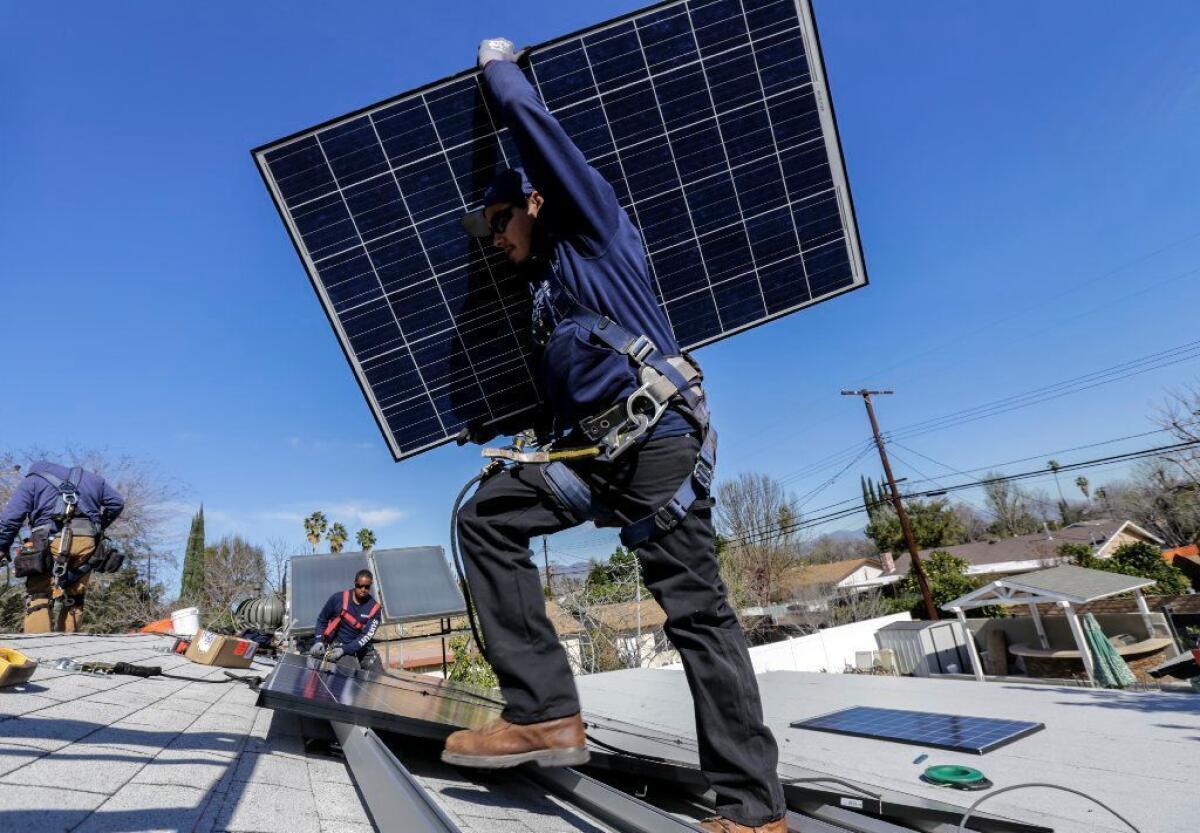 Alejandro DeLeon carries a solar panel as a crew from Sunrun installs a solar system on a home in Van Nuys in 2016.