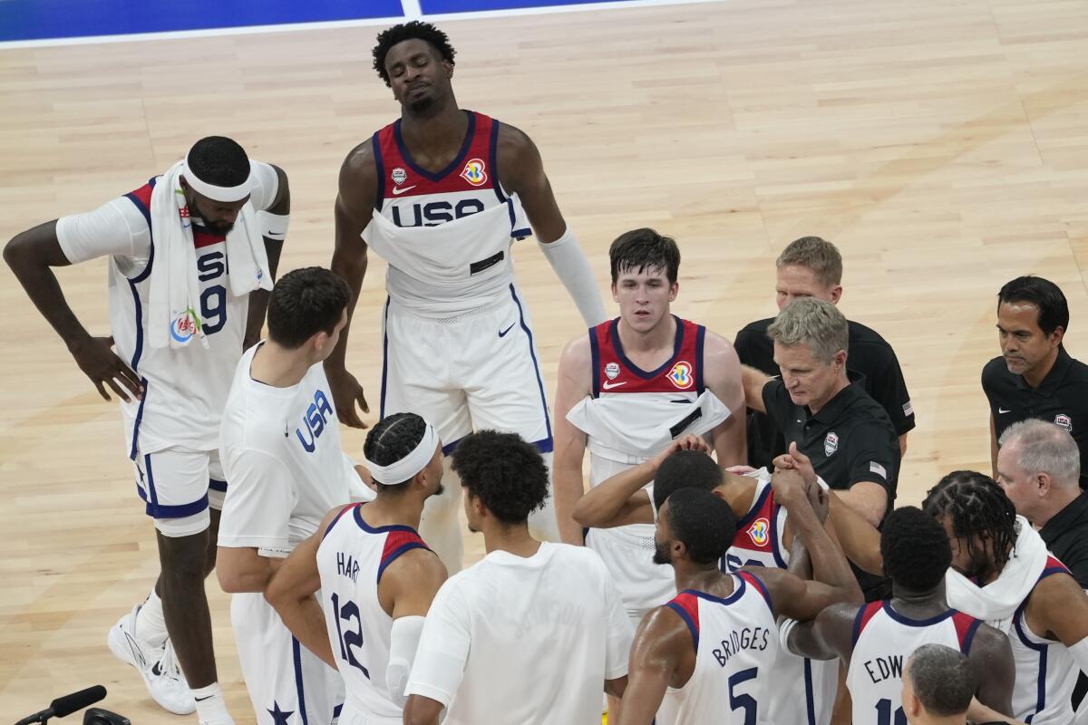 Austin Reaves, center, and teammates gather on the court after their loss to Germany 