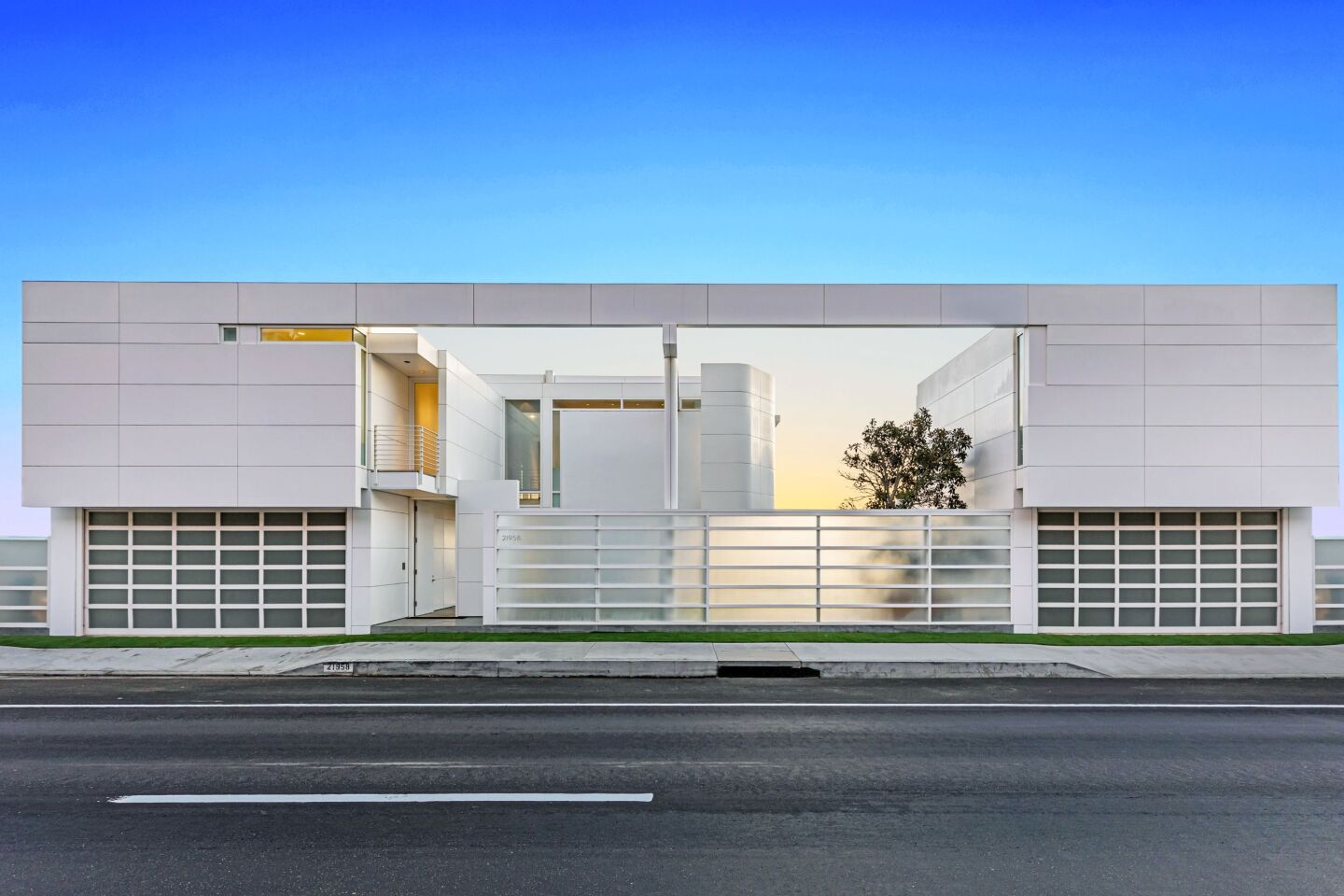 The white, modular exterior of the home is seen from the road.