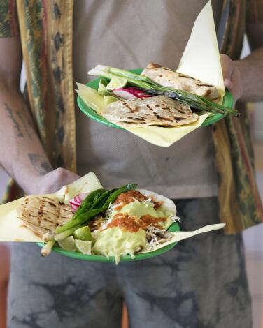 A person holding two plates laden with tacos