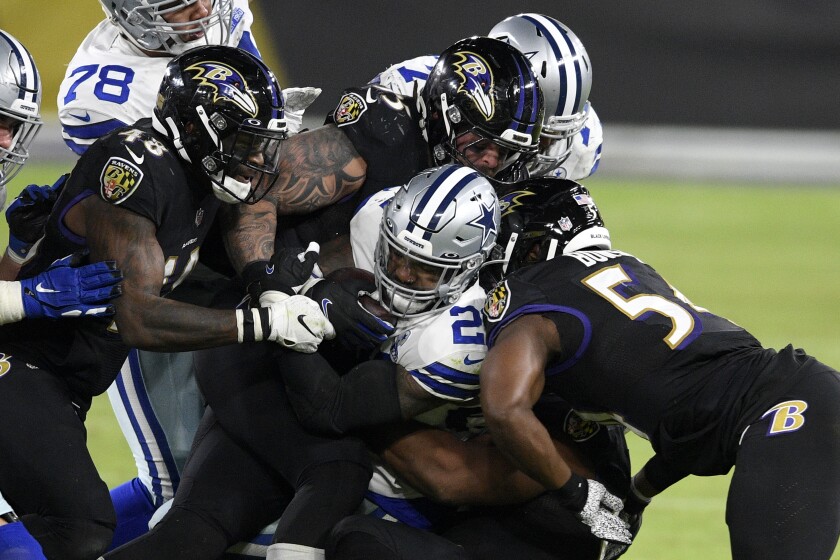 Dallas Cowboys running back Ezekiel Elliott, center, is brought down by a host of Baltimore Ravens defenders during the second half of an NFL football game, Tuesday, Dec. 8, 2020, in Baltimore. (AP Photo/Nick Wass)
