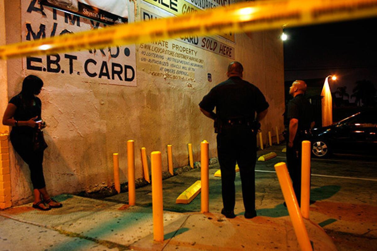 Police officers from the 77th Street Division look over a crime scene after a shooting near the corner of Western Avenue and Century Boulevard, near the two gangs' territories.
