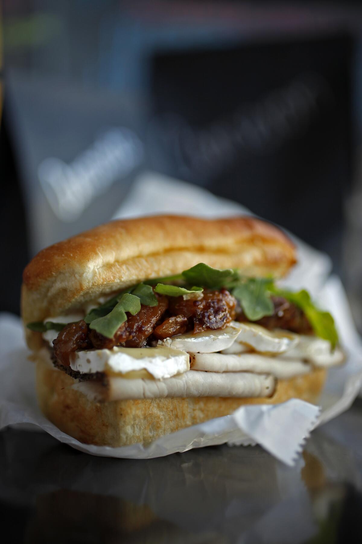 The Maple–Pepper Turkey Melt sandwich features Camembert, Mostarda, and Arugula. 