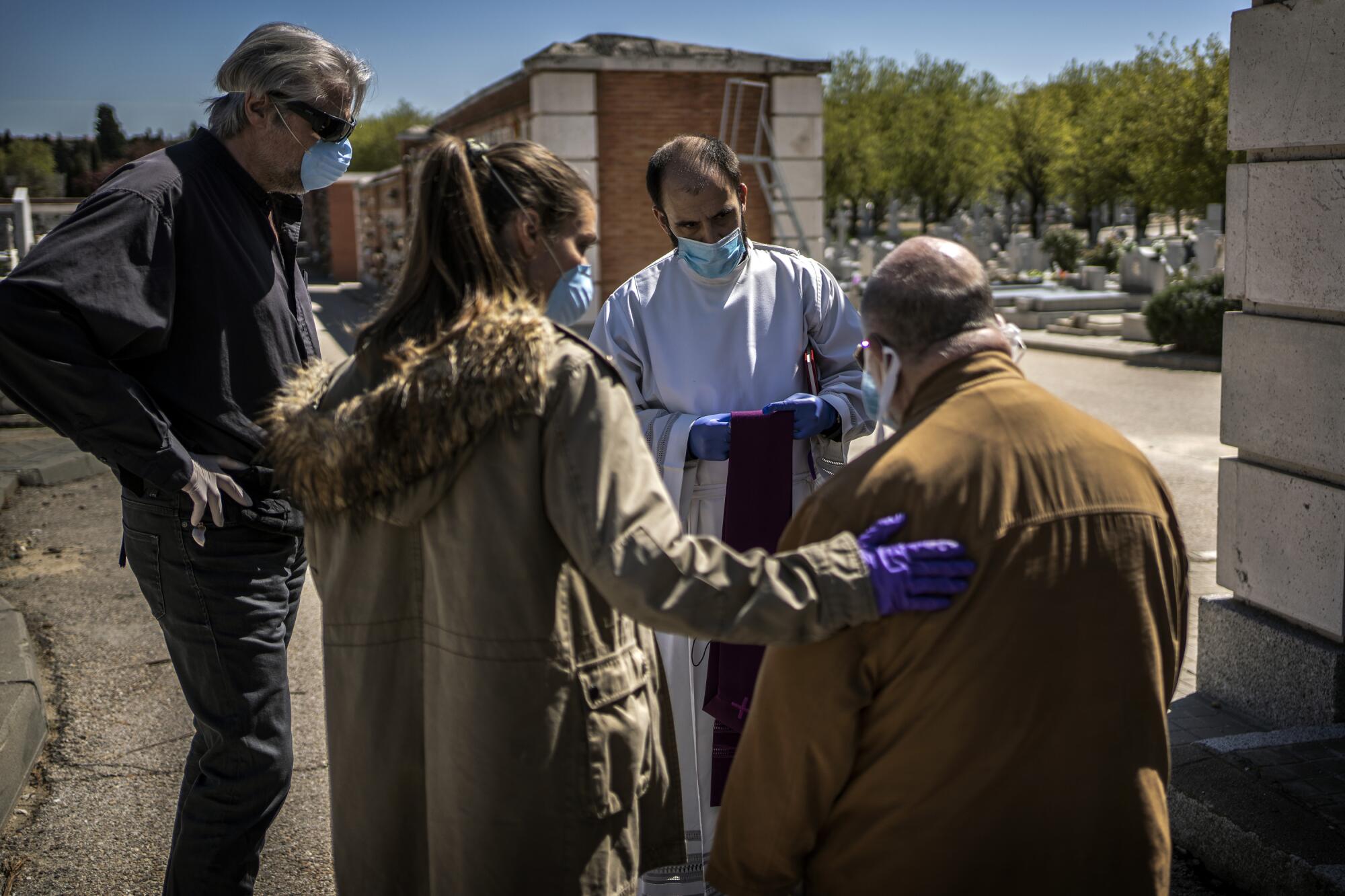 SPAIN:  Family members talk to a priest before the burial of a loved one, a victim of COVID-19, at the Almudena cemetery in Madrid.