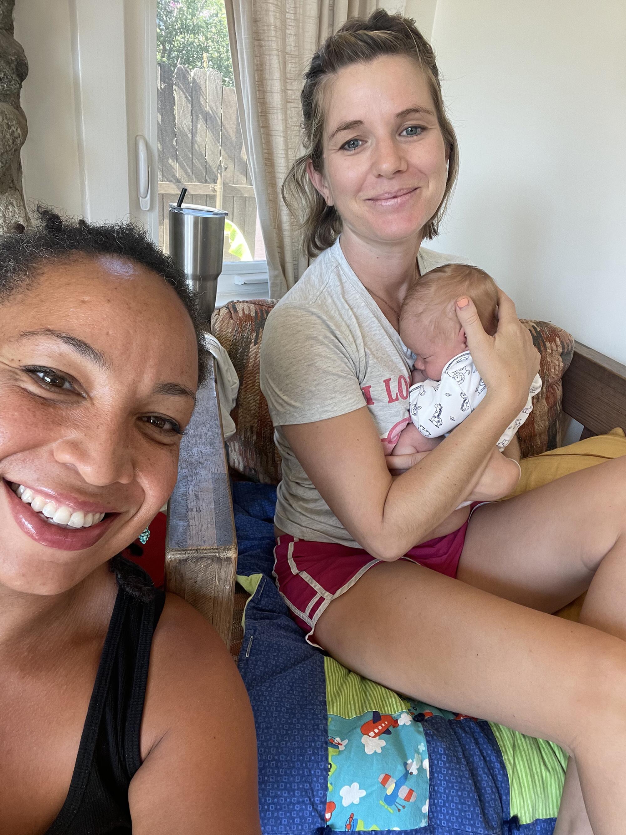 A woman smiles alongside a mother with her newborn