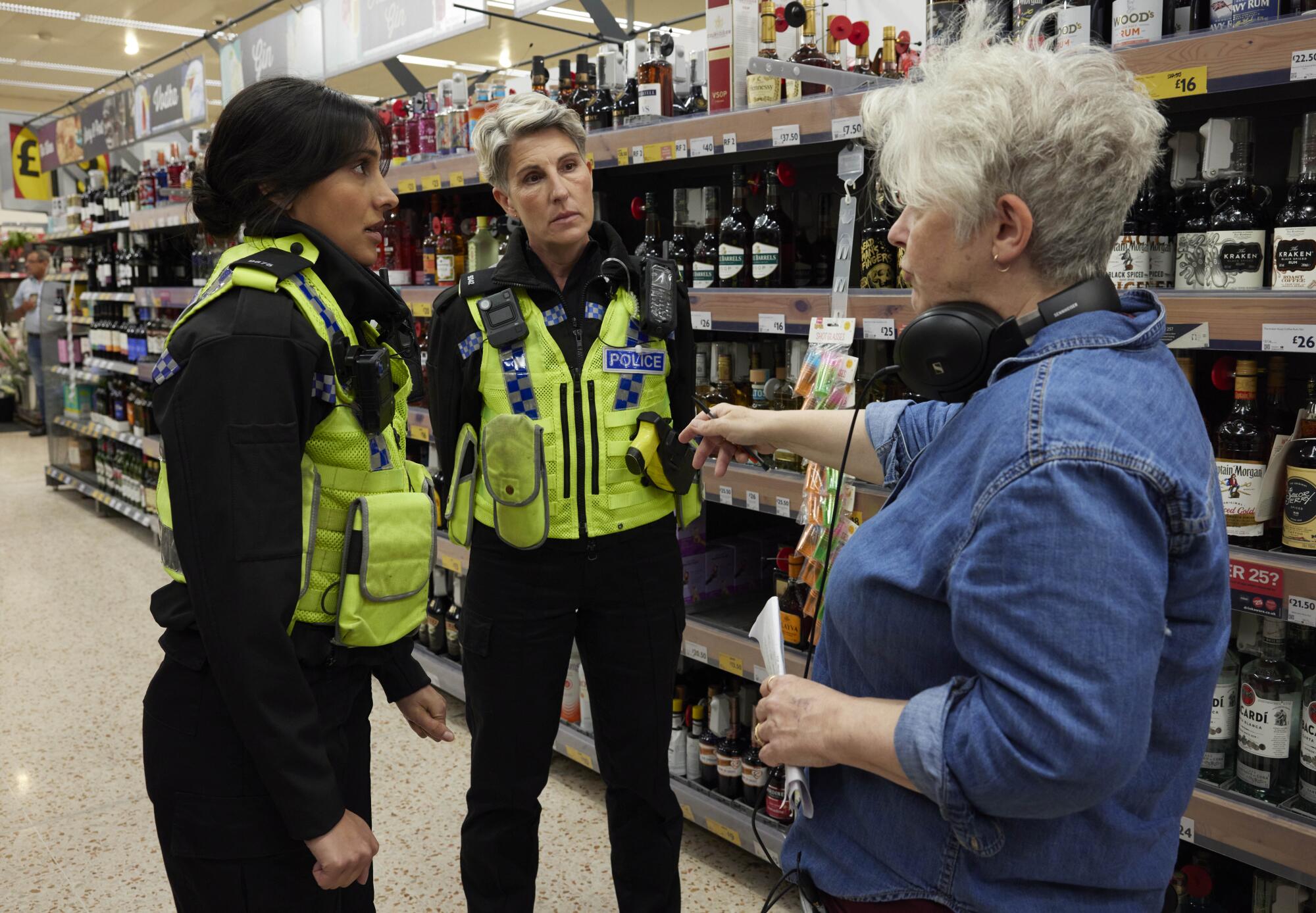 Taj Atwal and Tamsin Greig in yellow vests stand by Sally Wainwright in a blue shirt with headphones around her neck.