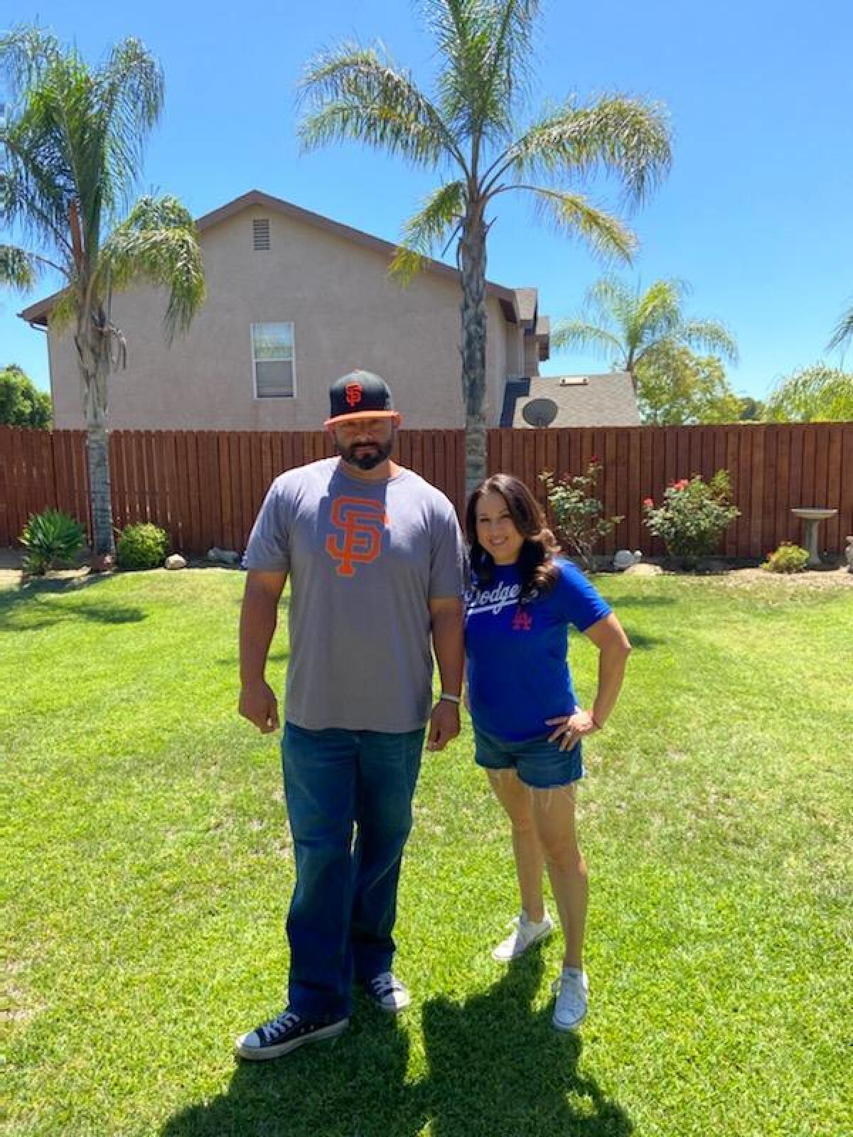 Sylmar baseball coach Ray Rivera and wife Lupe pose for a photo in their Giants and Dodgers shirts, respectively.