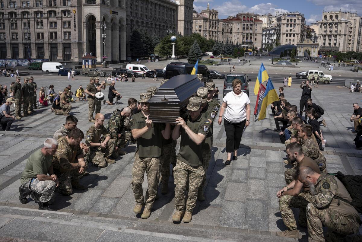 Ukrainian service memers carry a coffin in a public square.