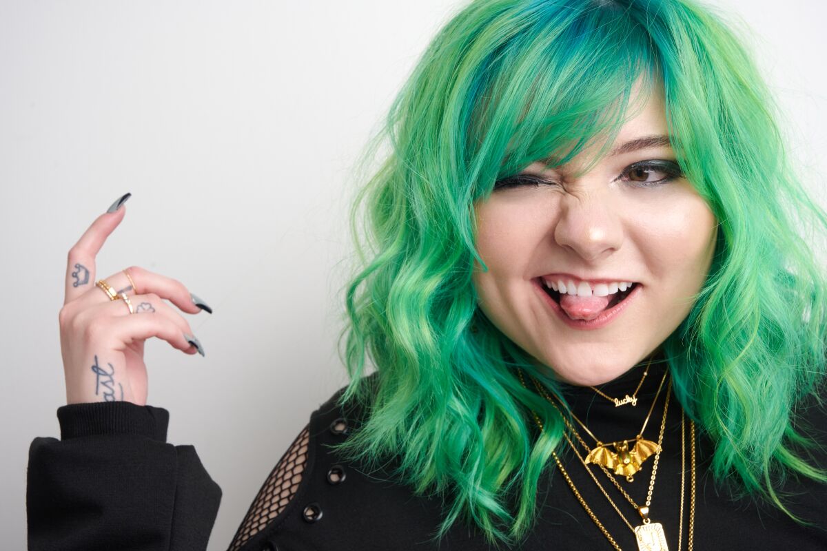 TikToker Jaci Butler, with green hair and several necklaces, poses for a portrait.