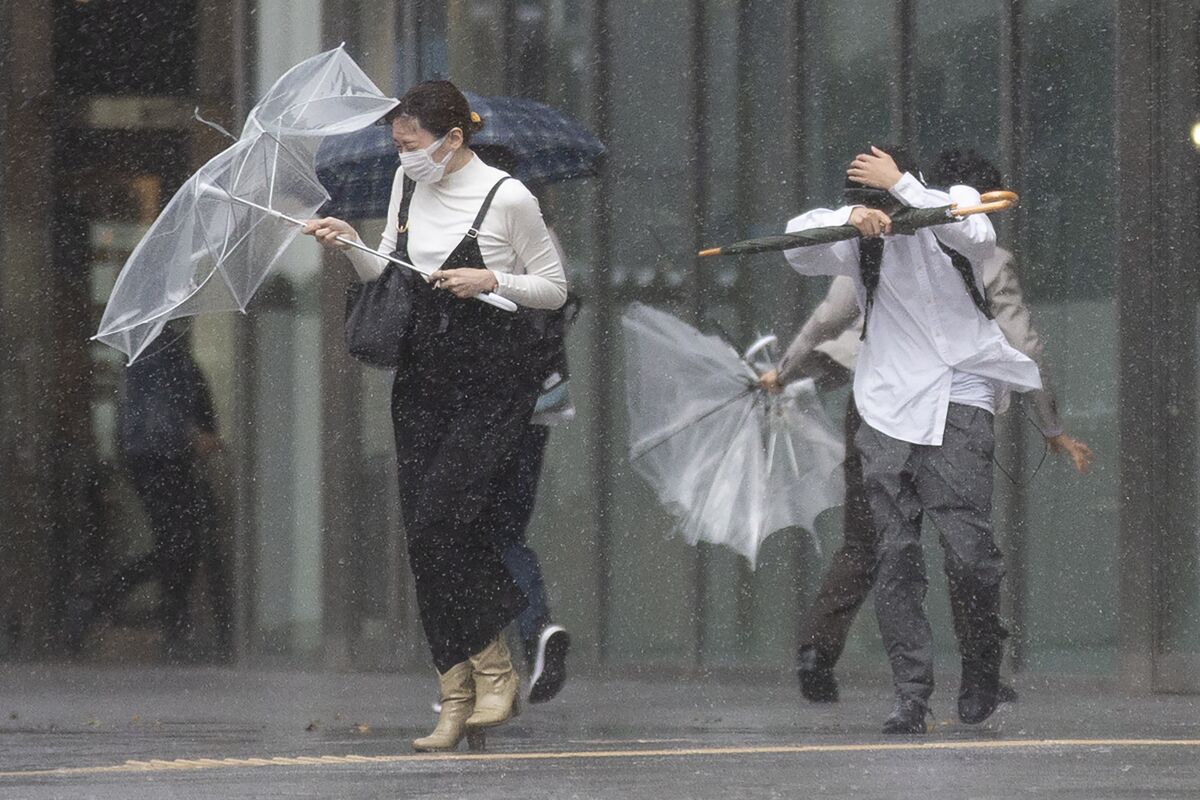 People struggle with rain and strong wind as Typhoon Mindulle travels off the coast of Japan Friday, Oct. 1, 2021, in Tokyo. (AP Photo/Kiichiro Sato)