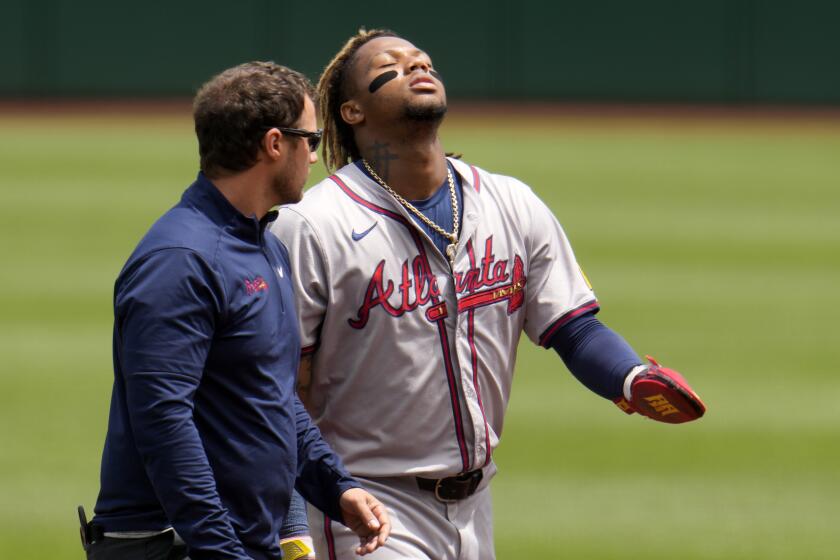 The Braves' Ronald Acua Jr. walks off the field with an athletic trainer after getting injured while running the bases 