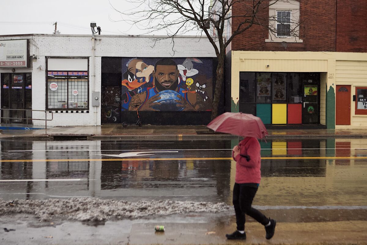 A person with an umbrella walks past the LeBron James “Space Jam” mural. 