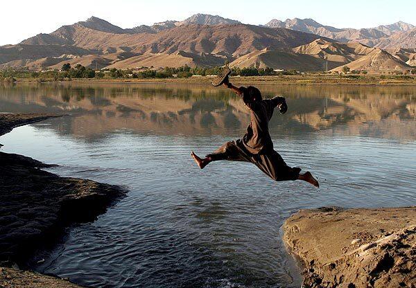 An Afghan boy makes his way over a stream. The U.S. is reviewing its strategy in Afghanistan, where the war is in its ninth year.
