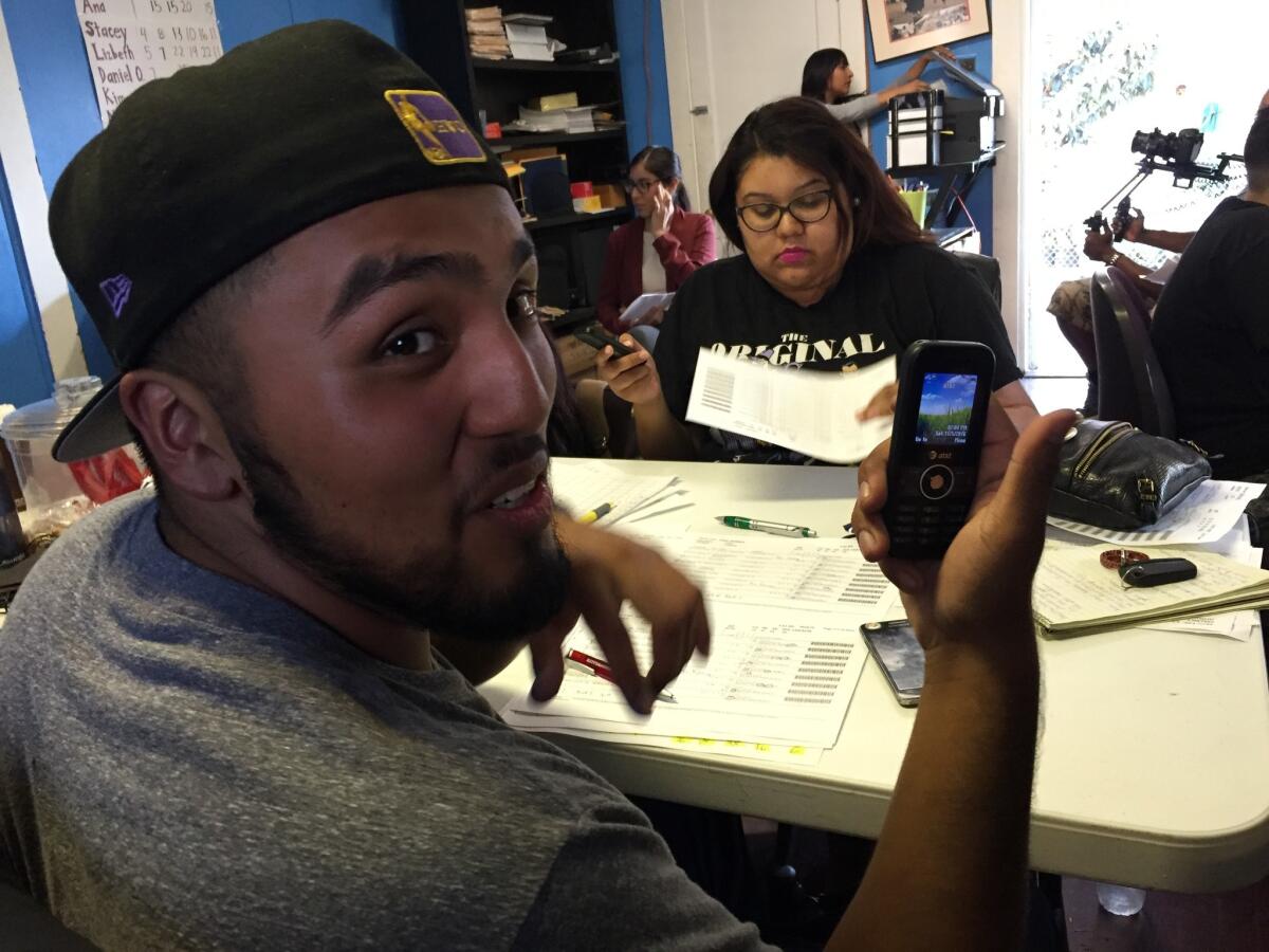 In South L.A., using phones provided by the Latino Voters League, Alfredo Campos, 19, and Kim Zamor, 26, ask Latino millenials to support Prop. 64, which legalizes and taxes marijuana for adult use. Campos said he hasn't used a phone like that since 7th grade.