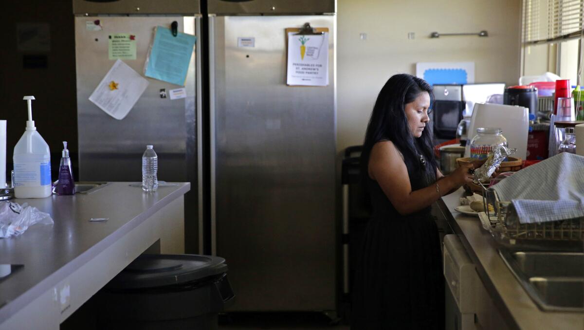 A woman stands at a kitchen counter, making a meal.