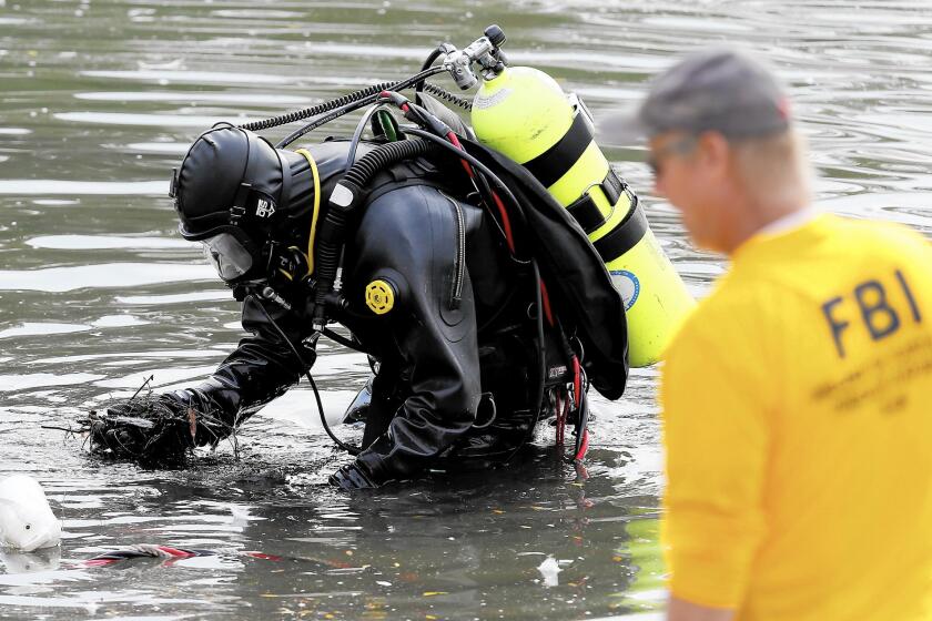 An FBI dive team on Thursday searches for electronic devices or other evidence possibly left in Seccombe Lake, about two miles north of the Inland Regional Center in San Bernardino.
