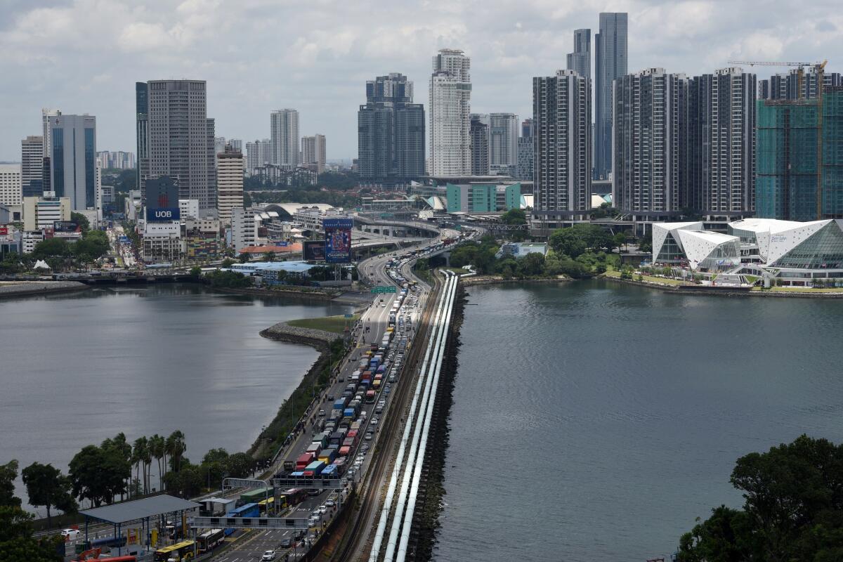 Vehicles line up to cross the causeway from southern Malaysia into Singapore on  March  17 ahead of a ban on overseas travel announced by Malaysia to curb the spread of the coronavirus.