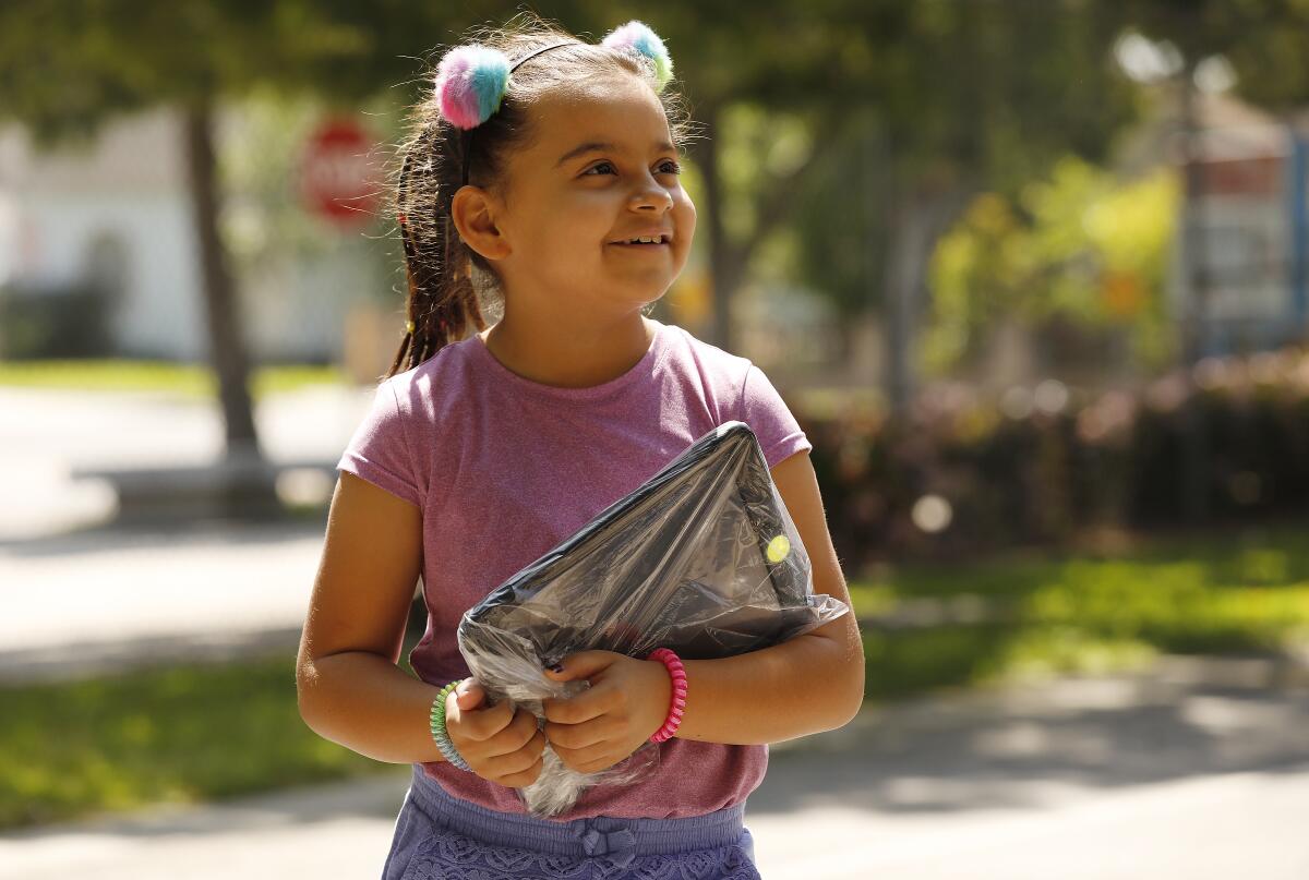 Paulina De Loza, 8, holds her a new computer issued to her