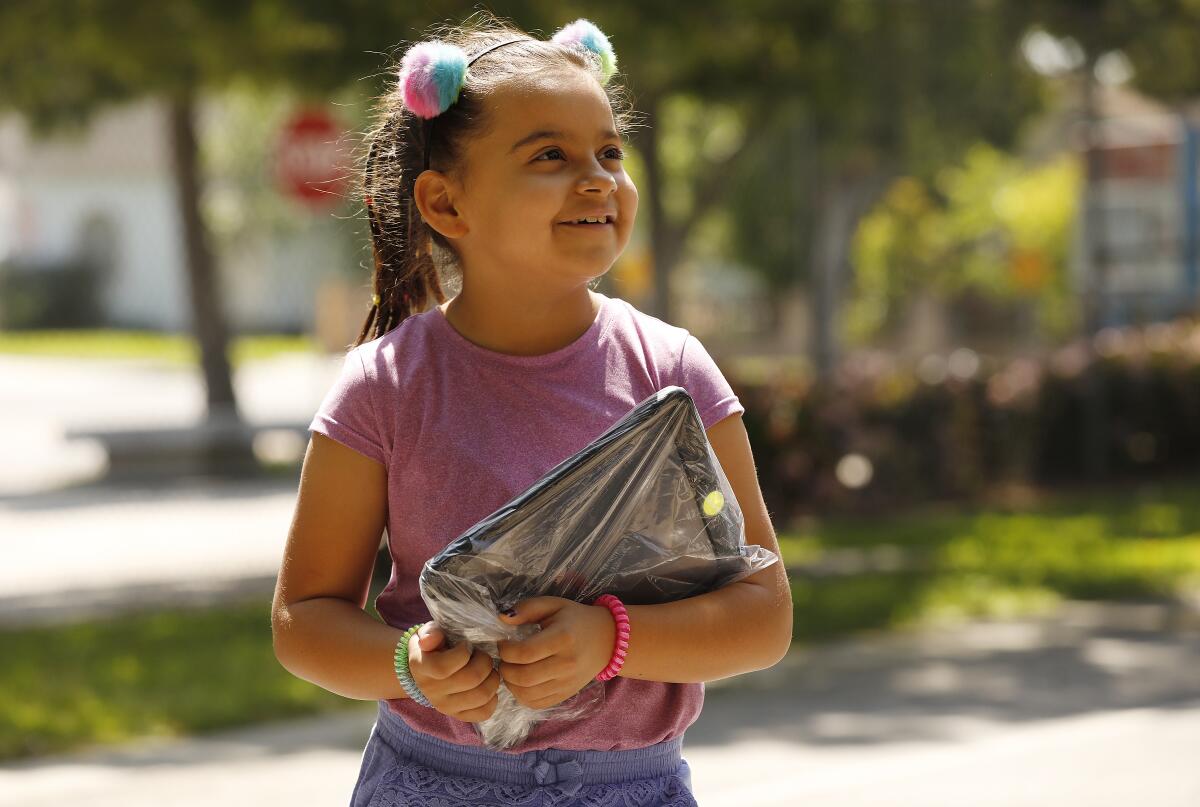 Paulina De Loza, 8, holds her a new computer issued to her 