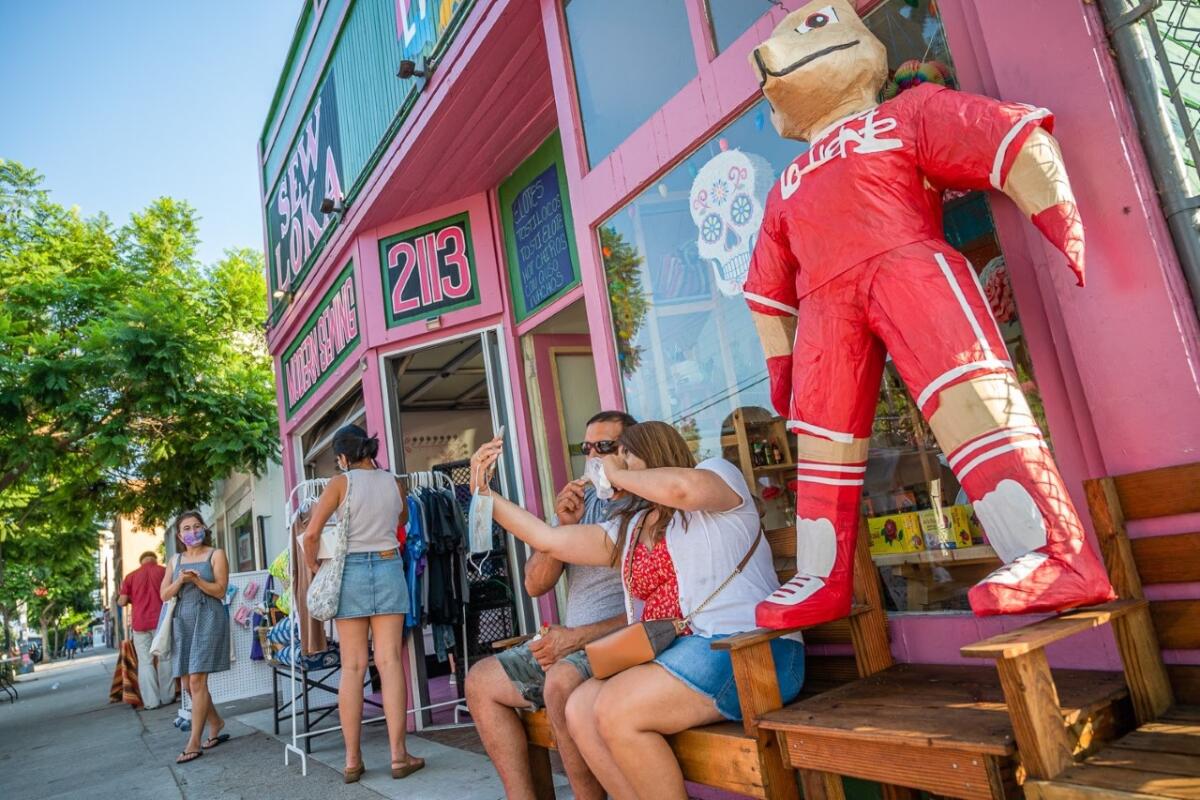 Customers browse merchandise and take photos outside Sew Loka during Walk The Block in Barrio Logan on Aug. 22, 2020