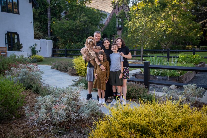 A family of five and a dog standing in a front yard.