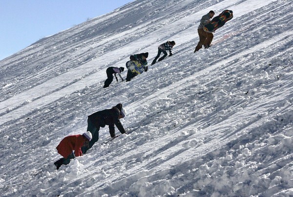 Snow lovers climb up a steep embankment in the San Bernardino National Forest off California 138, on the way to Wrightwood. Massive traffic jams on the road as well as California 2 forced travelers to park where they could so they could get out and enjoy the snow.