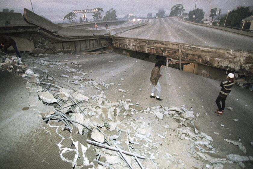FILE - In this Jan. 17, 1994 file photo, Interstate 10, the Santa Monica Freeway, split and collapsed over La Cienega Boulevard following the Northridge quake in the predawn hours in Los Angeles. Twenty-five years ago this week, a violent, pre-dawn earthquake shook Los Angeles from its sleep, and sunrise revealed widespread devastation, with dozens killed and $25 billion in damage. (AP Photo/Eric Draper, File)
