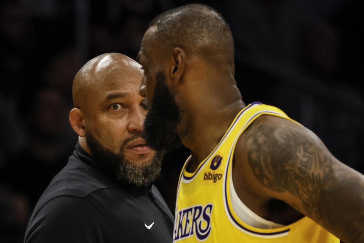Lakers coach Darvin Ham talks strategy with LeBron James along the sideline during a break in play.