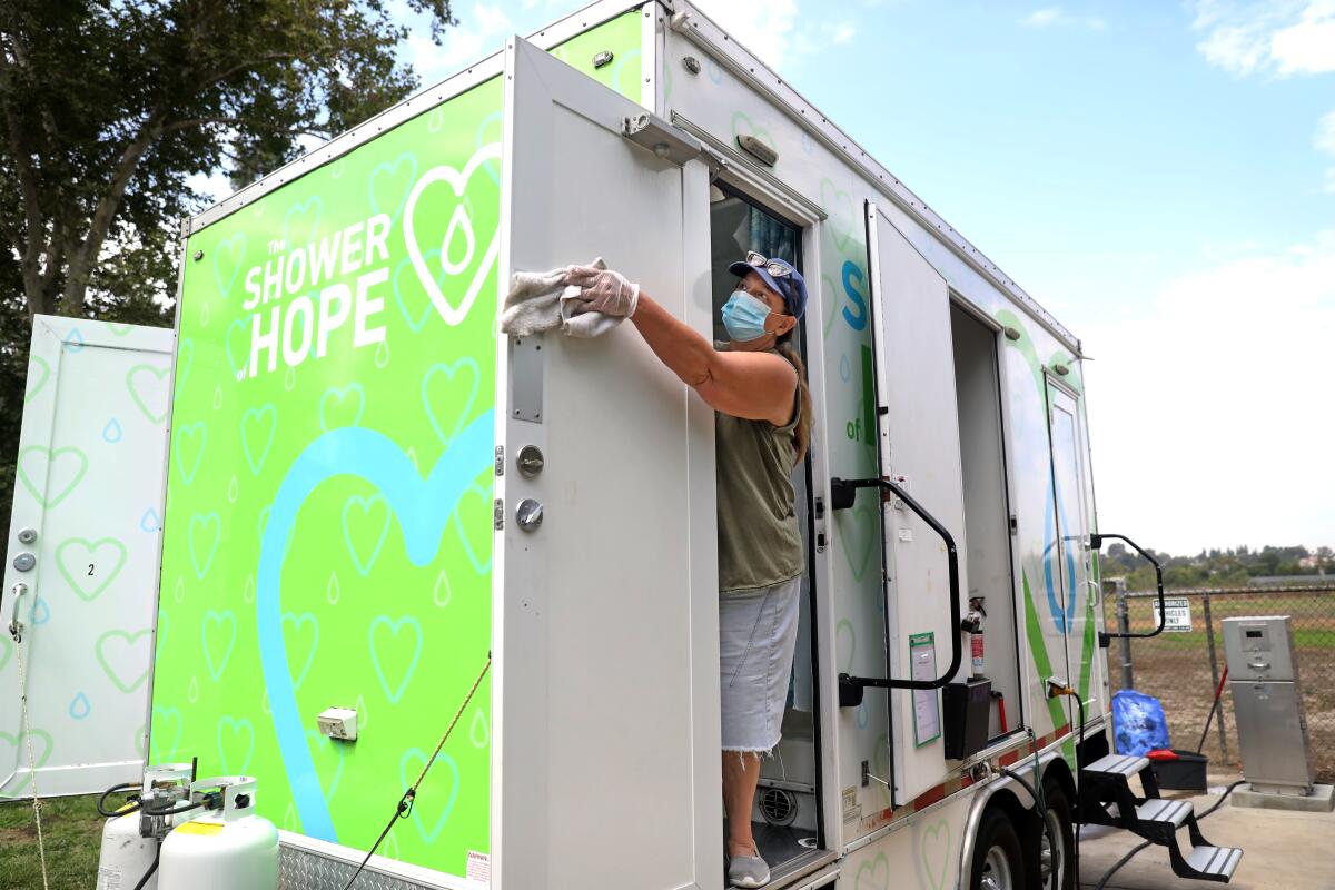 A woman cleans a mobile shower stall in Whitter Narrows Park in Rosemead. 