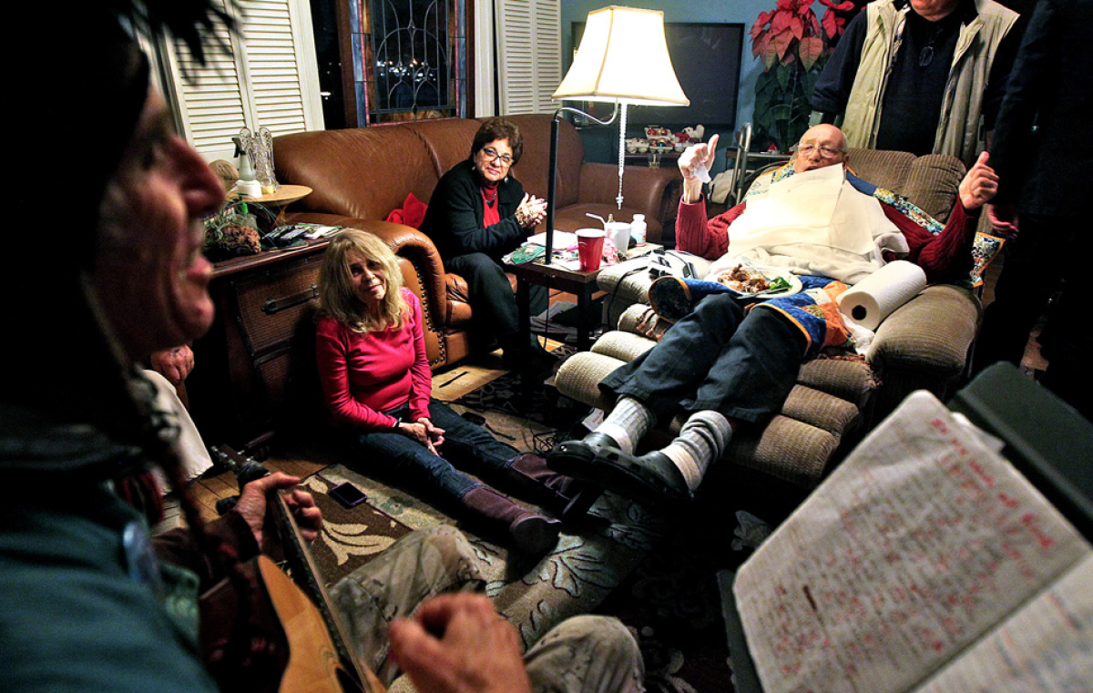 Bill Rosendahl, right, listens as Venice street performer Jingles, left, sings at the councilman's home in Mar Vista during a party marking the so-called Mayan apocalypse in December.