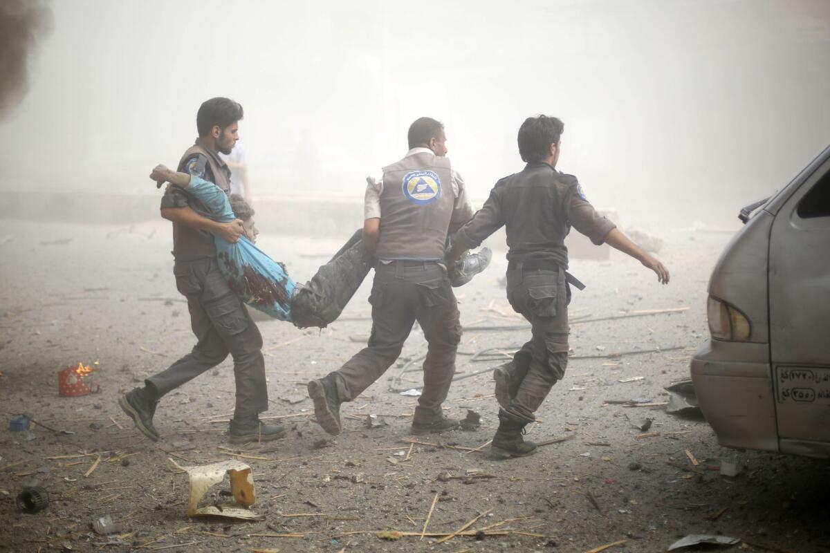Emergency personnel carry a wounded man following airstrikes on a marketplace in a rebel-held area of Douma, Syria, on Aug. 16.