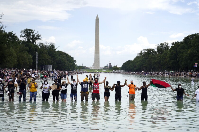 People join hands as they pose for a photo inside the Reflecting Pool in the shadow of the Washington Monument.