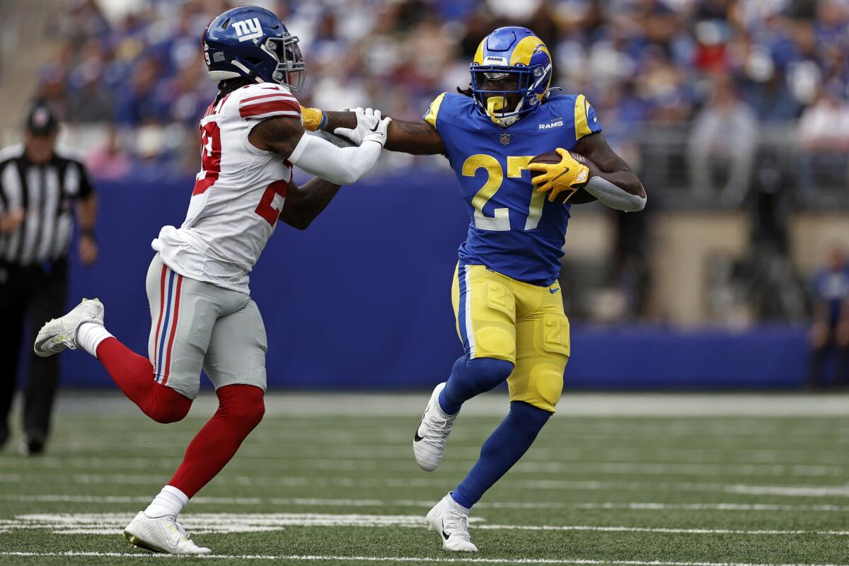 The Rams' Darrell Henderson gives  New York Giants safety Xavier McKinney (29) a stiff arm.