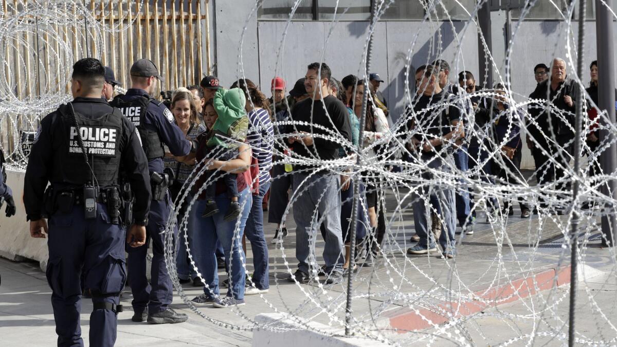 People line up to cross into the U.S. from Tijuana, Mexico, seen through barriers topped with concertina wire at the San Ysidro port of entry in San Diego on Nov. 19.