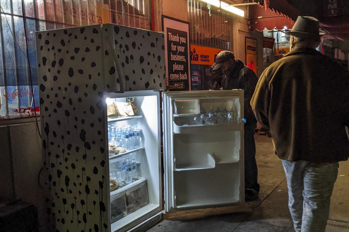 A person walks by a community fridge on an L.A. sidewalk