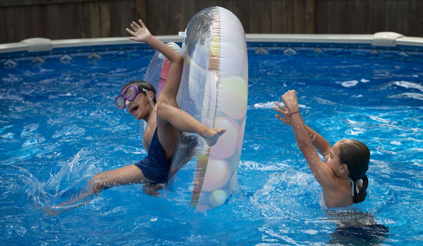 Twin sister Brooklynn Macan flips Bo into the pool at their home in Roeland Park, Kan. They were born 12 weeks early, but Brooklynn hasn’t had health issues like Bo’s.