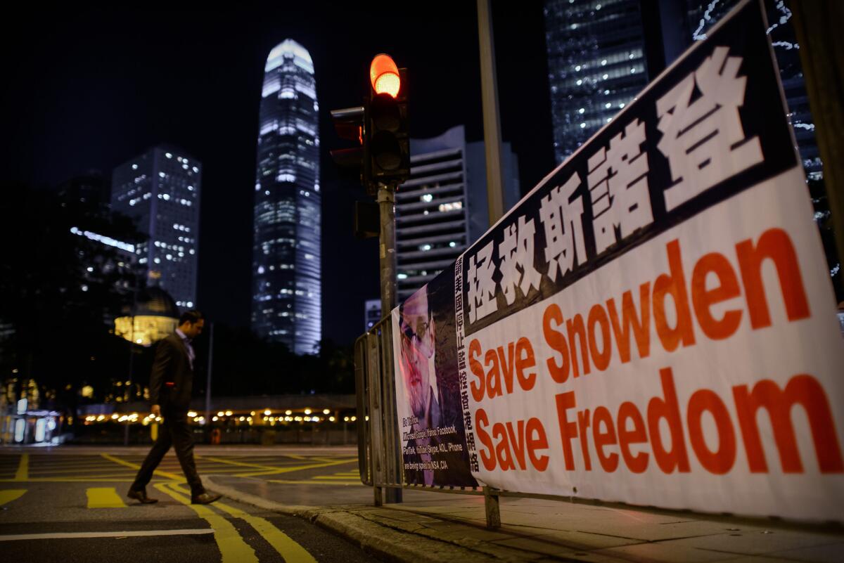 A man crosses a street next to banner displayed in support of former U.S. National Security Agency contractor Edward Snowden in Hong Kong.