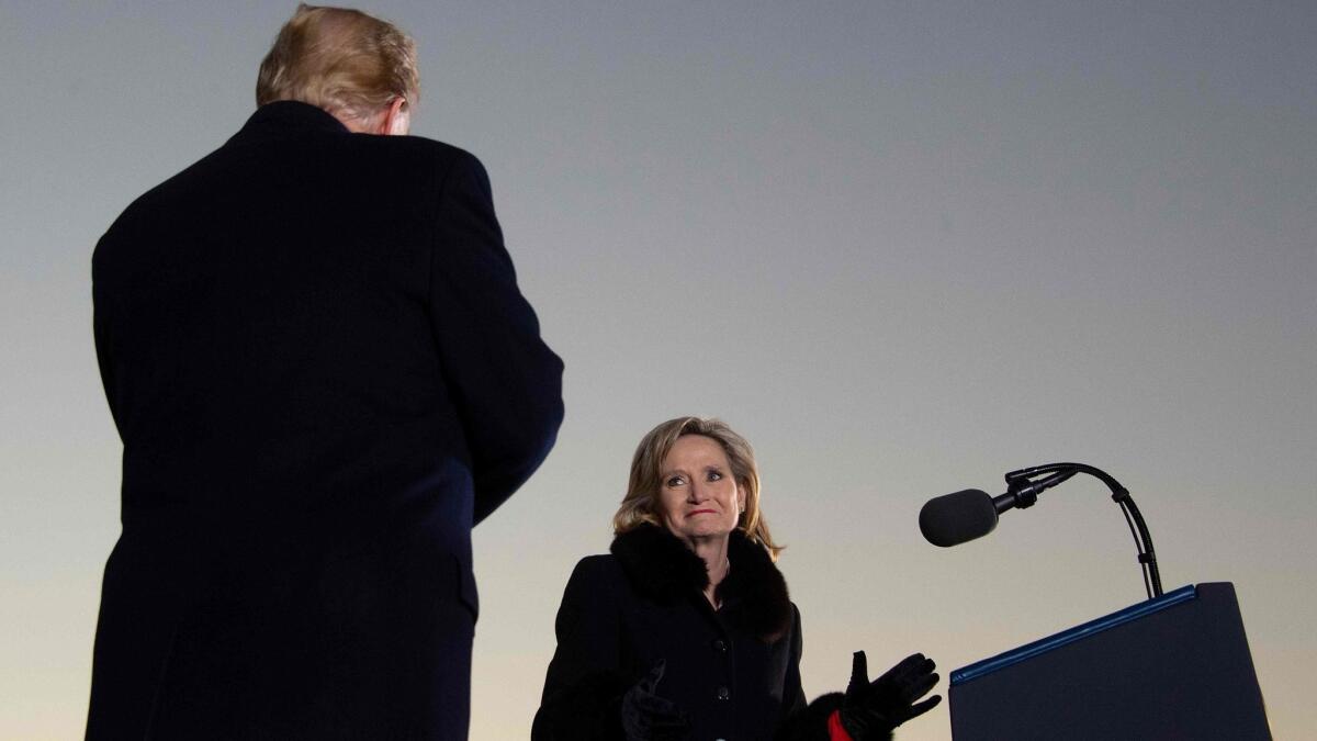 Republican Sen. Cindy Hyde-Smith of Mississippi glances at President Trump during a rally in Tupelo, Miss., on Monday, the eve of a special election runoff in which she's trying to keep her seat.